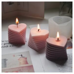 tres velas de colores morado, rosado y blanco en forma de espiral de corazones